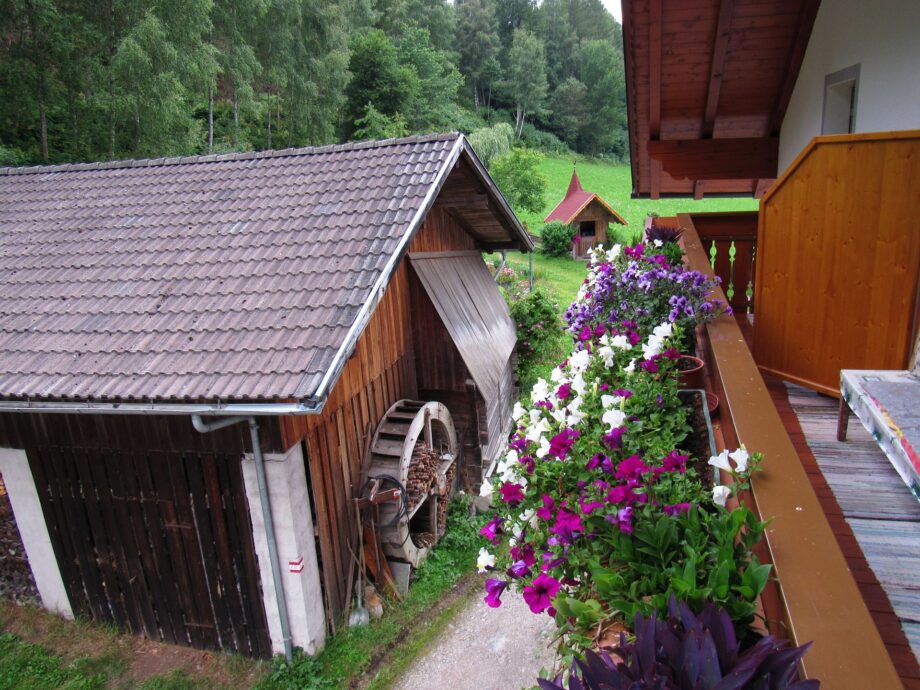 Balcone fiorito dell’appartamento Alpenrose affacciato su un edificio in legno