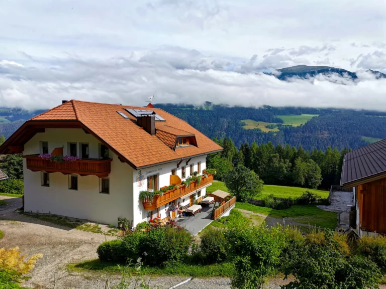 Il maso Hofer Hof sopra la valle con nubi basse sulle montagne