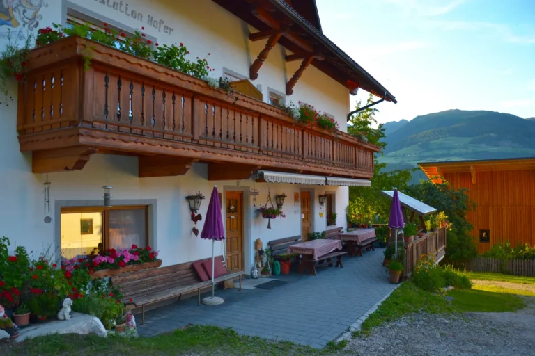 Panche e tavoli davanti alla facciata fiorita del maso Hofer Hof