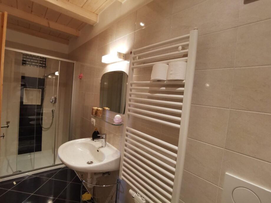 Lavabo, specchio e scaldasalviette nel bagno della camera Kamelie