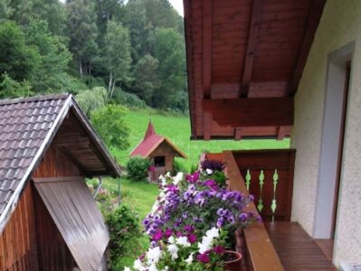 Balcone fiorito della camera Kamelie con vista sul bosco