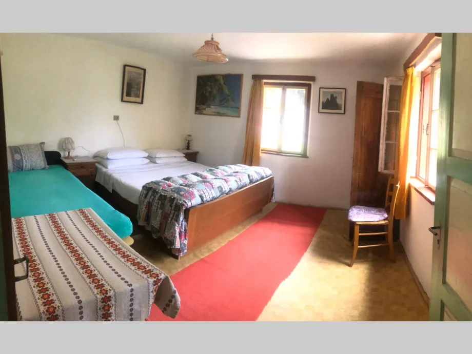 Camera della dependance al primo piano con letto matrimoniale e finestre luminose