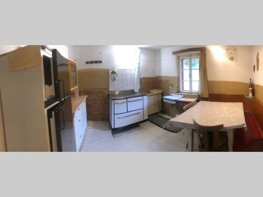 Cucina della dependance al primo piano con fornelli, tavolo e frigorifero