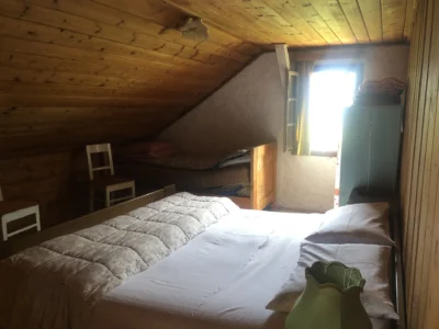 Camera mansardata della dependance con due letti e soffitto in legno