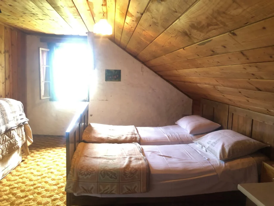 Seconda camera mansardata della dependance con due letti sotto il tetto in legno