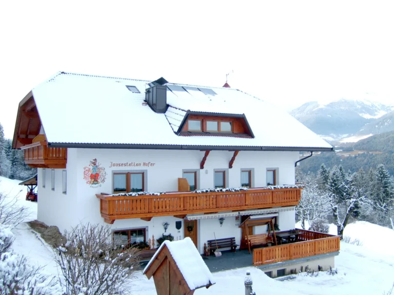 Facciata e balconi in legno del maso Hofer Hof sotto la neve