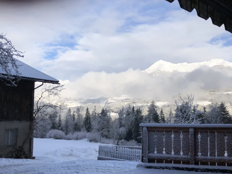 Terrazza innevata del maso Hofer Hof con vista sulla valle fra le nuvole