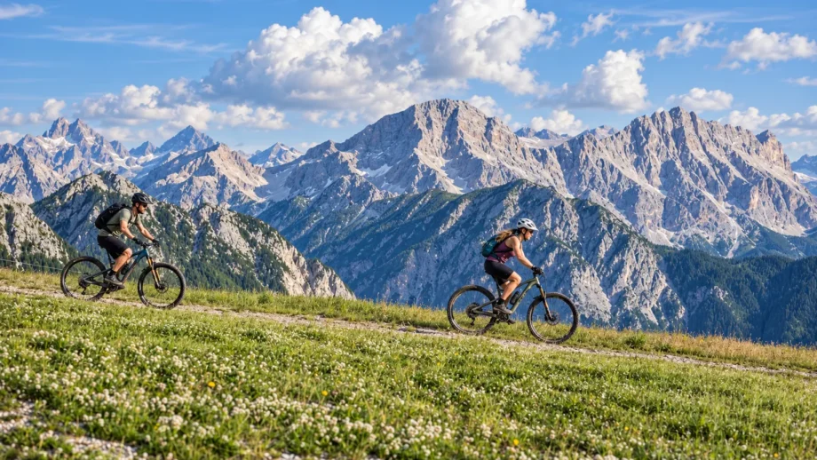 Due ciclisti in mountain bike su un sentiero con le Dolomiti sullo sfondo